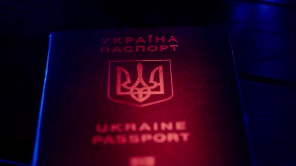 パスポートと移行クリエイティブ広告コンセプト アイデンティティ文書を閉じる ブルーウクライナのパスポート 赤色のライトでテーブルに国家シンボル — ストック動画