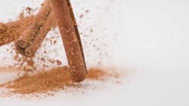 Aromatik baharatlar yaratıcı reklam konsepti. Yemek malzemelerinin stüdyo çekimlerini kapat. Kahverengi kurutulmuş tarçın çubukları beyaz arka planda üstten dökülüyor, etrafa saçılıyor..