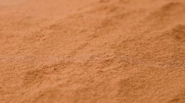 Aromatik baharatlar yaratıcı reklam konsepti. Spice 'ın stüdyo çekimlerini kapat. Kahverengi kurutulmuş tarçın tozunun arka planında kesirler ve çerçevenin tepesinden bir kaç çubuk bir yüzeye düşüyor..