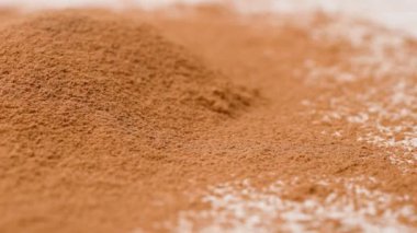 Aromatik baharatlar yaratıcı konsept reklamları. Baharatların stüdyo çekimlerini kapat. Tarçın çubukları tarçın tozu yığınının üzerine düşer. Küçük parçalar farklı yönlere uçar.