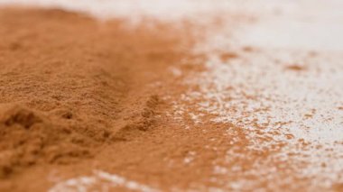 Aromatik baharatlar yaratıcı konsept reklamları. Baharatların stüdyo çekimlerini kapat. Tarçın çubukları tarçın tozu yığınının üzerine düşer. Küçük parçalar farklı yönlere uçar.