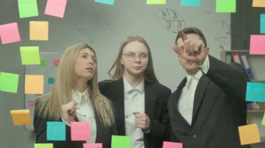 Modern iş dünyasının yaratıcı konseptinde beyin fırtınası ve fikirler. Ofis planlama projesindeki şirket liderinin portresi. İş arkadaşları cam duvara proje satış planını tartışıyor.