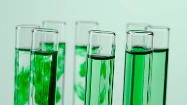 Bilim ve biyoteknoloji yaratıcı kavramı. Beyaz arka plandaki laboratuvar camlarını kapatın. Şeffaf ve mavi sıvılı test tüpleri ve çözünen mavi madde bulutu