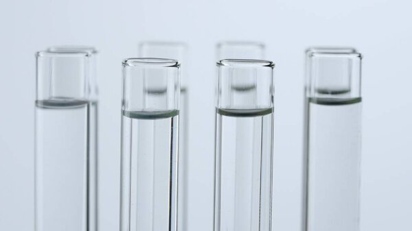 Science and biotechnology creative concept. Close up shot of laboratory glassware on white background. Test tubes with transparent liquid fluid in laboratory, scientific expertise.
