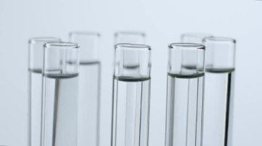 Bilim ve biyoteknoloji yaratıcı kavramı. Beyaz arka plandaki laboratuvar camlarını kapatın. Platformda dönen sıvılı test tüpleri, kişi iki tüp içinde mavi sıvı ekler..