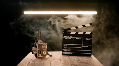Duman kaplı ahşap bir masanın üzerinde eski model bir video kamera. Bir stüdyoda, neon lambanın aydınlattığı siyah bir arkaplanda görüntü ekipmanı.