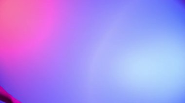El, siyah bir el çırpma tahtası ya da film tahtası tutuyor. Mavi arka planda, pembe neon ışıkla aydınlatılmış dairesel bir ışık var. Sinema endüstrisi, eğlence