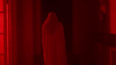 Korku filmi ve kötü ruh yaratıcı reklam konsepti. Evde hayalet kadın portresi var. Yüzü peçeli beyaz elbiseli bir kadın kırmızı parlayan bir yıldırımla odada yürüyor..