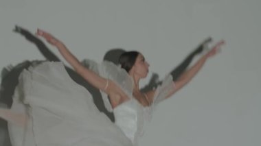 Klasik ve modern bale yaratıcı reklam konsepti. Stüdyoda sahne ışıkları altında beyaz arka plandaki kadın portresi. Sivri uçlu ayakkabılı ve beyaz tüllü balerin sahnesini yakından çek..