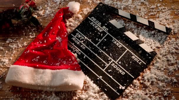 Снег Покрывает Доску Киношных Хлопушек Рождественскую Шляпу Еловую Ветку Деревянном — стоковое видео