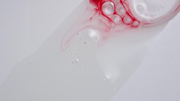 액체와 창조적인 배경에 물질의 닫습니다 빨간색 잉크가있는 거품은 화장품 표면에 — 비디오