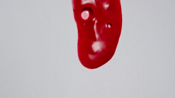 ゲルクリエイティブ広告コンセプト 白い背景に透明物質のショットを閉じます 赤い着色された化粧品のゲル液体か明確な表面で流れる血清 — ストック動画