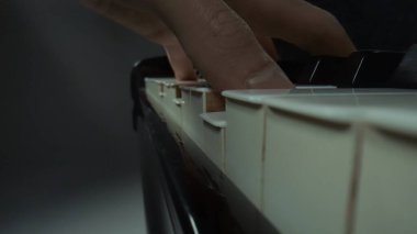 Müzik ve enstrümanlar yaratıcı reklam konsepti. Klasik piyano ve müzisyenin stüdyo çekimini kapat. Piyano tuşlarında melodi çalan erkek eller, enstrümantal melodi çalan profesyonel sanatçılar.