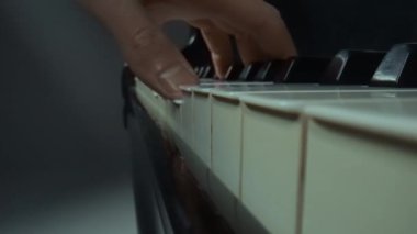 Müzik ve enstrümanlar yaratıcı reklam konsepti. Klasik piyano ve müzisyenin stüdyo çekimini kapat. Piyano tuşlarında melodi çalan erkek eller, enstrümantal melodi çalan profesyonel sanatçılar.
