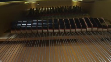 Müzik ve enstrümanlar yaratıcı reklam konsepti. Klasik piyanonun stüdyo çekimini kapat. Piyanonun içinde çekiçle yavaşça tellere vurup tuşların hareketini yansıtıyor..
