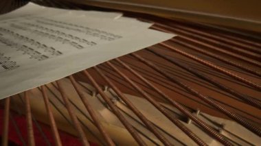 Müzik ve enstrümanlar yaratıcı reklam konsepti. Klasik piyanonun stüdyo çekimini kapat. Piyanonun içinde müzik notaları olan kompozisyon kağıtlarıyla çekilmiş.