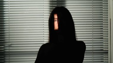 Yaratıcı vücut tanıtım konseptinin güzelliği. Stüdyoda kadın modelin portresi. Cazibeli kadın silueti, yüzünün bir kısmını jaluzi ile pencerenin önünde gösteren ışık..