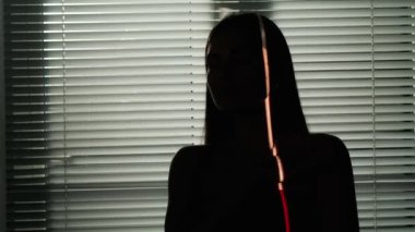 Vücut estetiği yaratıcı reklam konseptinin güzelliği. Stüdyoda çekici bir kadın modelin portresi. Cazibeli kadın silueti. Vücudunun bir kısmını pencerenin yanında panjurlarla gösteren ışık.