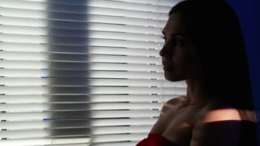 Vücut estetiği yaratıcı reklam konseptinin güzelliği. Stüdyoda çekici bir kadın modelin portresi. Kadın silueti mavi neon arka plan. Işık vücudun tepesine doğru hareket ediyor. Pencerenin yanında duruyor..