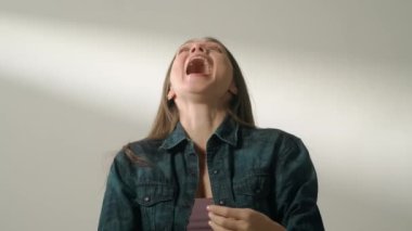 İnsani aşırı duygular yaratıcı reklam konsepti. Çekici kadın modelin olumlu ruh hali portresi. Esmer kadın, günlük giysiler içinde stüdyoda oturuyor ve mutlu bir şekilde alkışlıyor..