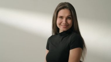 İnsani aşırı duygular yaratıcı reklam konsepti. Çekici kadın modelin olumlu ruh hali portresi. Esmer kadın, günlük giysiler içinde stüdyoda oturuyor ve gülümsüyor..