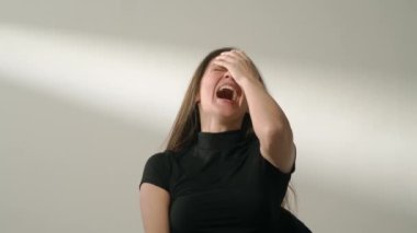 İnsani aşırı duygular yaratıcı reklam konsepti. Çekici kadın modelin olumlu ruh hali portresi. Esmer kadın, günlük giysiler içinde stüdyoda oturuyor ve kameraya yüksek sesle gülüyor..