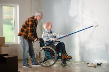 Çekim, tadilatın yapıldığı odayı gösteriyor. Bir çift tamirat yapıyor, duvarları beyaz boyayla boyuyorlar. Kadın tekerlekli sandalyede, adam ona yardım ediyor. Çok dikkatliler..