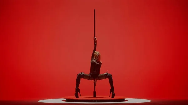 Modern dance style and choreography creative concept. Portrait of young female dancer in the studio. Professional pole dancer girl dancing on pylon, showing modern pole dance, red neon background.