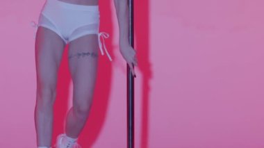 Modern dans tarzı ve koreografi yaratıcı konsepti. Stüdyodaki genç bayan dansçının portresi. Profesyonel striptizci kız direğin üstünde dans ediyor, modern direk dansı gösteriyor, pembe arka plan..