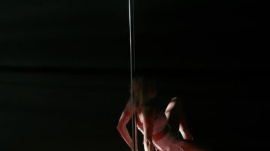 Modern dans tarzı ve koreografi yaratıcı konsepti. Stüdyoda genç bir bayan dansçı. Profesyonel striptizci kız pilon üzerinde dönüyor, modern kutup performansı gösteriyor, siyah arkaplan.