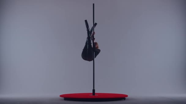 一名身穿黑色透明连衣裙的年轻女子跳撑杆跳编舞 穿着高跟鞋的舞蹈家在灰色背景的工作室里色情地跳舞 — 图库视频影像