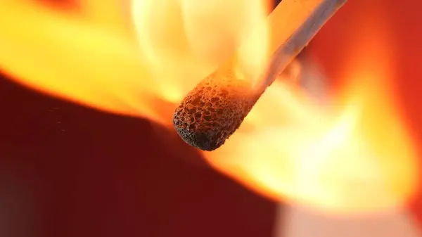 マクロは赤いスタジオの背景との燃える試合を撮影した 燃える試合の炎が暗い空間を照らしています 燃える試合は オレンジ 活気に満ちたダイナミックな炎に包まれています — ストック写真
