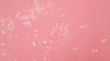 Pembe arkaplandaki yakın planda su kabarcığı var. Hava akımından gelen su kabarcığı. Farklı boyutlardalar. Çok fazlalar. Suyun hareket ettiğini gösteriyorlar..