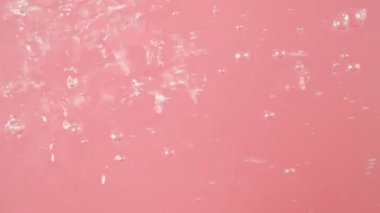 Pembe arkaplandaki yakın planda su kabarcığı var. Hava akımından gelen su kabarcığı. Farklı boyutlardalar. Çok fazlalar. Suyun hareket ettiğini gösteriyorlar..