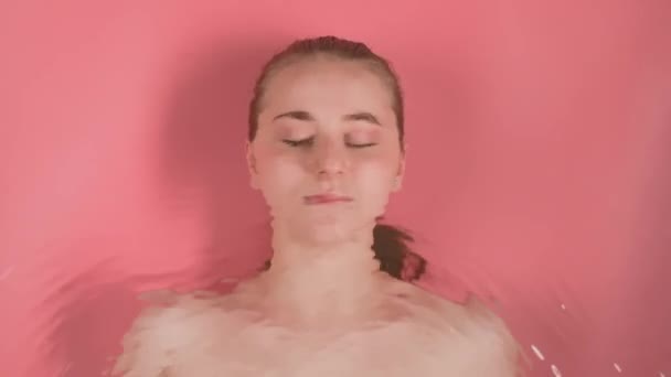 분홍색 배경에 메이크업 소녀입니다 그녀는 수중에 누워있는 것으로 추정된다 그녀의 — 비디오