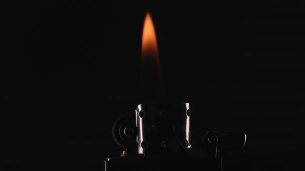 ガソリンライターの点火と燃焼の瞬間は 黒い背景にキャプチャされます マクロショットでライターの明るくダイナミックな炎 エキサイティングな視覚効果を生み出します — ストック動画