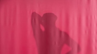 Pembe bir perdenin arkasında banyo lifi ile yıkanan bir adamın silüeti. Bir adam perdeyi geri çeker, vücudunu şoka sokar, bir bez atar ve perdenin arkasına saklanır. Gözetlerken
