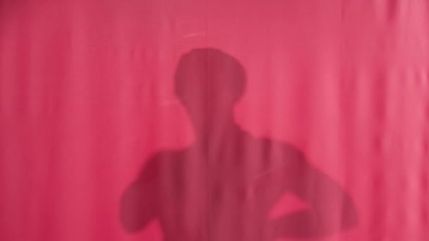 ピンクのシャワーカーテンで洗濯している男のシルエット 男はカーテンを後ろに引っ張ってまっすぐ見て シャワーカーテンをもう一度閉じる — ストック動画