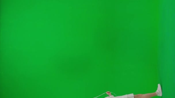 子どもたちクリエイティブなコンセプト スタジオで小さな女の子 クロマキーグリーンスクリーンの赤いヘリウム風船の白いドレスの小さな女の子は 周りを見回して笑顔を隔離しました バーティカルビデオ — ストック動画