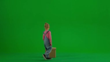 Çocukların yaratıcı konsepti. Stüdyoda küçük bir kızın portresi. Kot pantolonlu küçük bir kız ve krom anahtarlı at kuyruklu yeşil ekran izole bir arka plan, kutudan kırmızı bir balon çıkıyor, mutlu bir yüz..