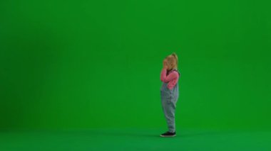 Çocukların yaratıcı konsepti. Stüdyoda küçük bir kızın portresi. Küçük kız gözleri kapalı duruyor, annesi balonlarını getiriyor, kız mutlu ve şaşkın, yeşil ekran arka planında..