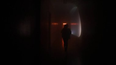 Terk edilmiş yerler ve boş binalar yaratıcı reklam konsepti. Karanlık koridorda kırmızı neon ışıklı bir kadın portresi. Elinde fenerle bodrumda hızla koşan bir kadın, kamera kızı kovalıyor.