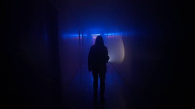 Terk edilmiş yerler ve boş binalar yaratıcı reklam konsepti. Karanlık koridorda neon ışıklı bir kadın portresi. Elinde fenerle bodrumda yürüyen bir kadın keşfediyor.,