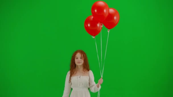 子どもたちクリエイティブなコンセプト スタジオの小さな女の子の肖像画 クロマキーグリーンスクリーンの赤い風船の白いドレスの小さな女の子は カメラを見て歩いている背景を隔離しました 肯定的な顔 — ストック動画