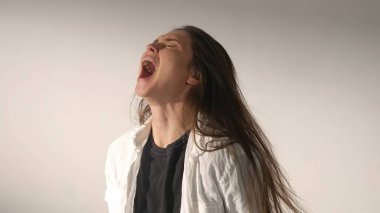 İnsani aşırı duygular yaratıcı reklam konsepti. Çekici kadın modelin olumsuz ruh hali portresi. Esmer kadının histerik bir ruh hali içinde el ele tutuşup çığlık attığı bir stüdyo fotoğrafı..