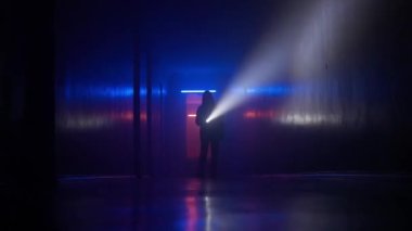 Terk edilmiş yerler ve boş binalar yaratıcı reklam konsepti. Karanlık koridorda neon ışıklı bir kadın portresi. Yere bakan kızdan el feneriyle kameraya doğru yürürken çekilmiş..