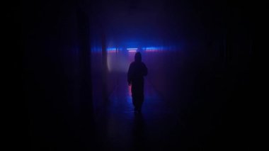Terk edilmiş yerler ve boş binalar yaratıcı reklam konsepti. Koridorda neon ışıklı bir insan portresi. Koridorda yürüyen el feneri olan kimyasal korumalı bir adam..