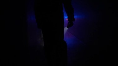 Terk edilmiş yerler ve boş binalar yaratıcı kavramlar. Koridordaki neon ışıkta siluet portresi. Kimyasal koruma giysisi giyen ve el feneriyle koridorda yürüyen biri..