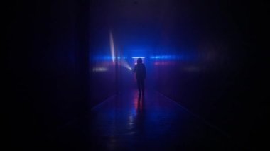 Terk edilmiş yerler ve boş binalar yaratıcı reklam konsepti. Karanlık koridorda neon ışıklı bir kadın portresi. El feneriyle bodrum tünelinde yürüyen düşük basınçlı bir kadın..