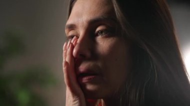İnsani aşırı duygular yaratıcı reklam konsepti. Çekici kadın modelin olumsuz ruh hali portresi. Kapalı çekim esmer kadın yüzü depresif bir halde ağlıyor ve gözyaşlarını siliyor..